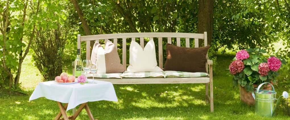 Gemütliche Holzbank im sommerlichen Garten von Pension Kreuzer 